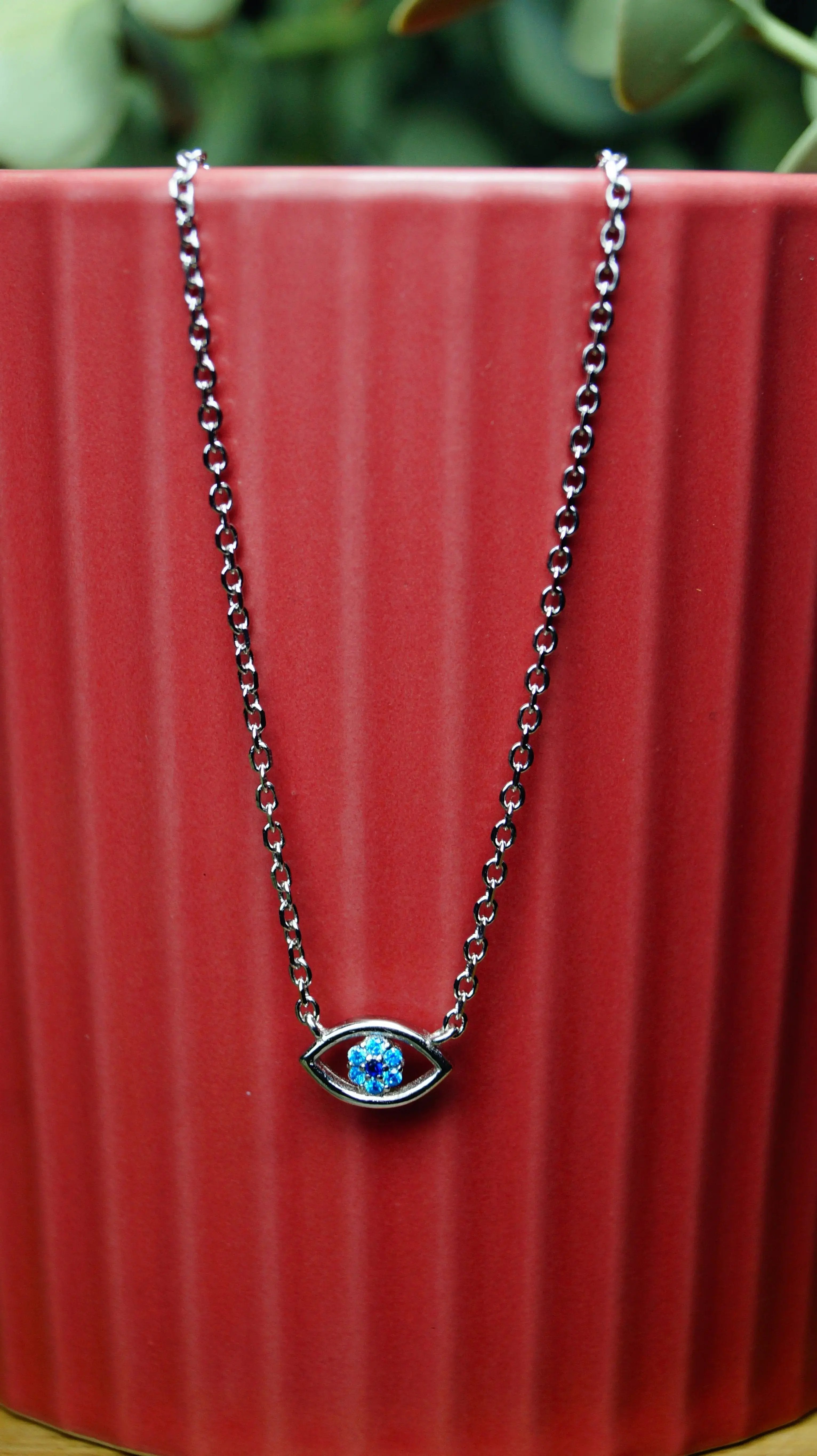 Necklace with a blue gemstone on a red textured surface