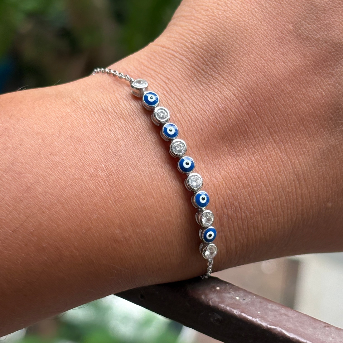Bracelet with blue and white eye-shaped beads on a wrist against a blurred background