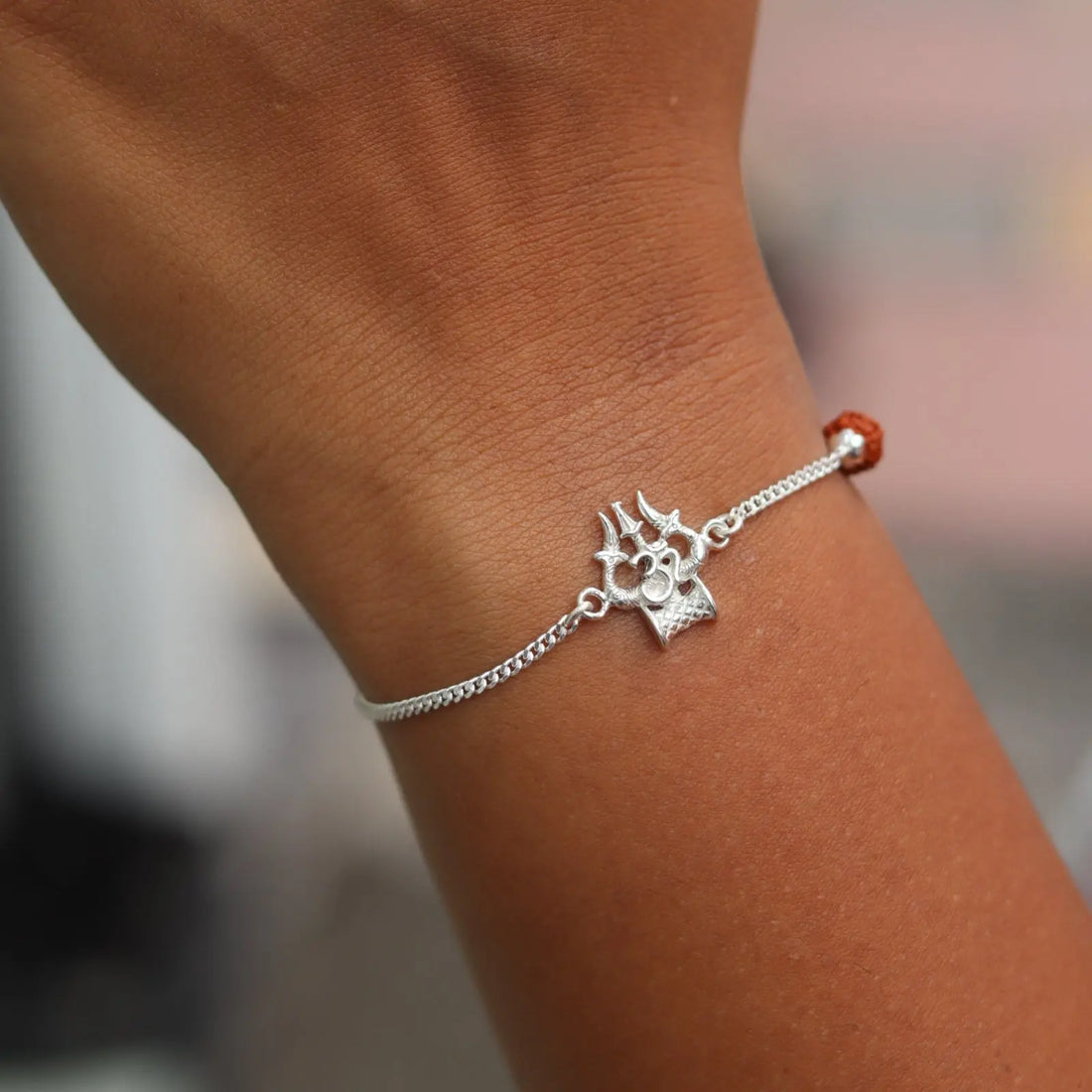 Silver bracelet with a decorative charm on a wrist against a blurred background