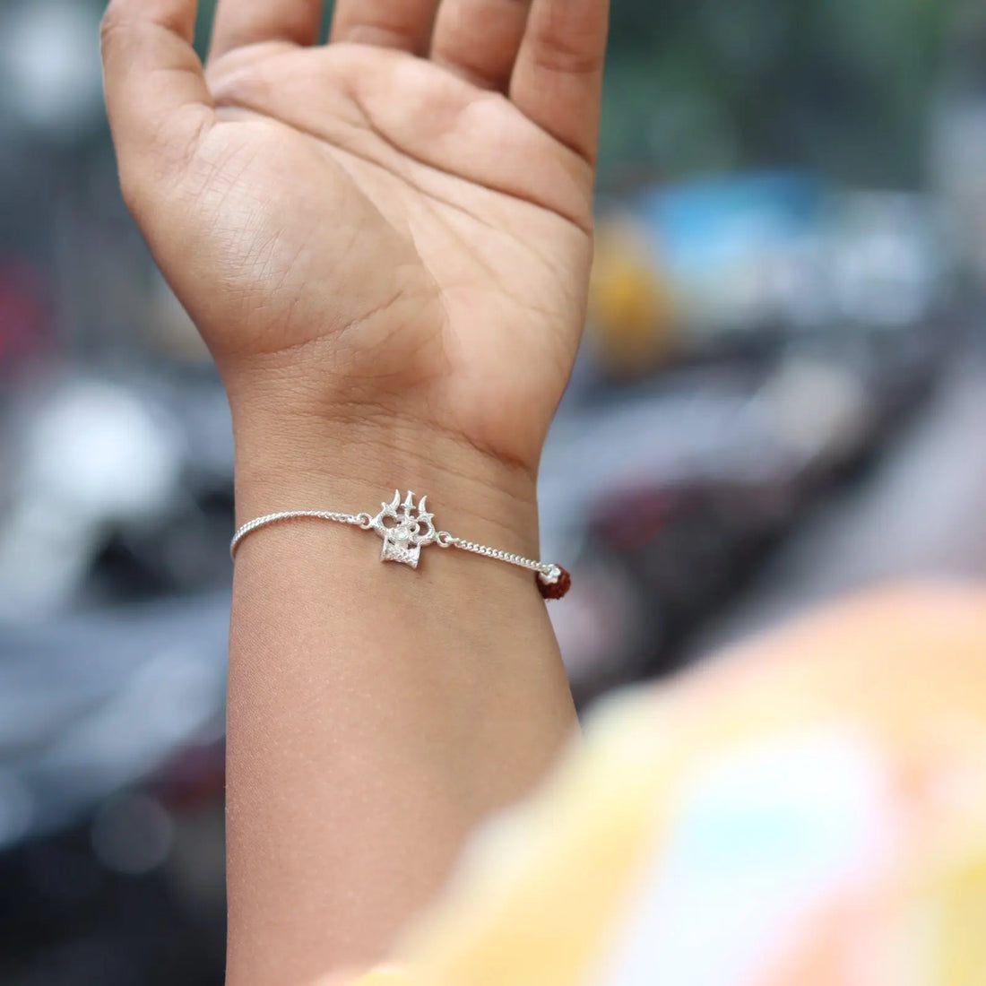 Silver bracelet with a decorative charm on a wrist against a blurred background